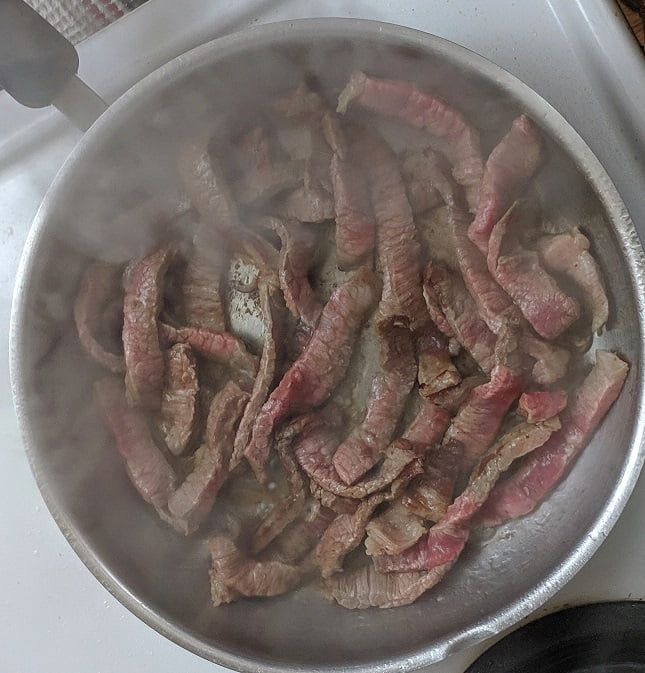 Adding sliced onions to the beef
