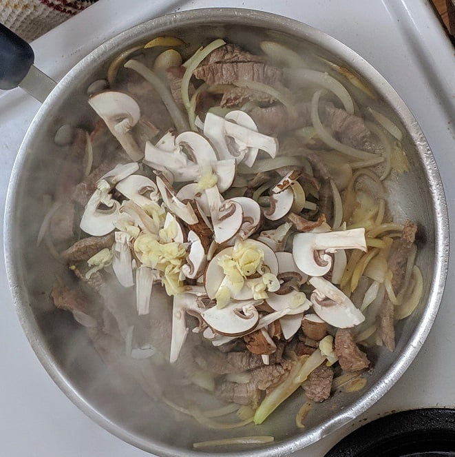 Mushrooms softening in the pan with the beef