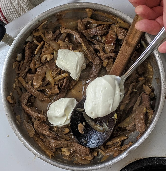 Stirring sour cream into the sauce