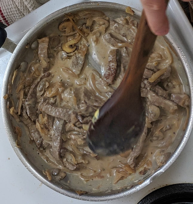 Seasoning the stroganoff with salt and pepper
