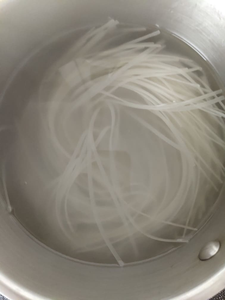 Rinsed rice noodles draining in a colander