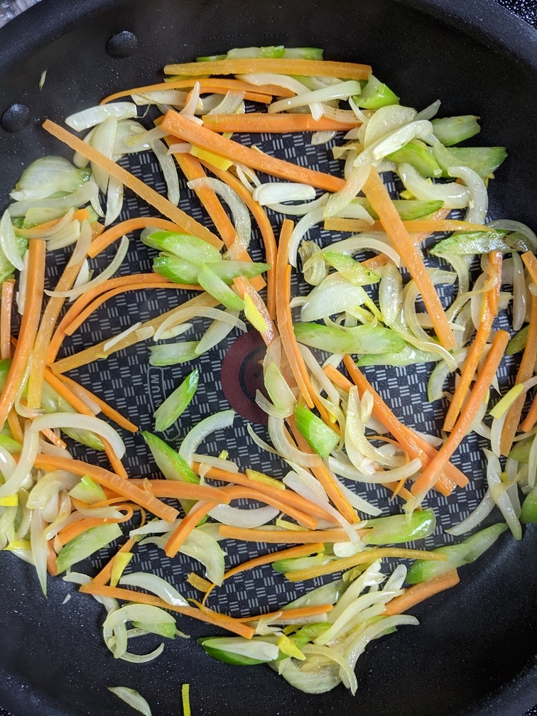 Cabbage, bean sprouts, and pork added to the pan