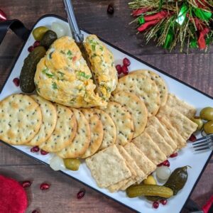 A cheese ball with crackers and pickles
