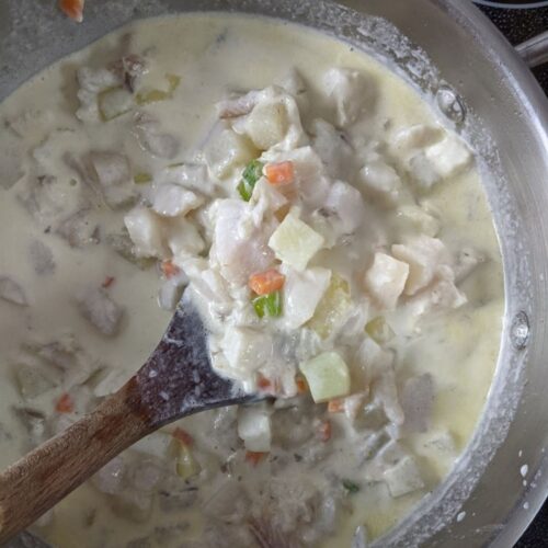 A pot of Nova Scotia Fish Chowder with chunks of white fish and potato, with bits of carrot, onion, and celery