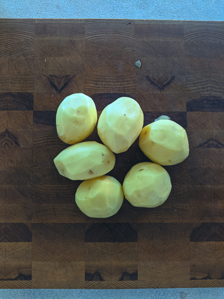 Peeled yellow potatoes on a cutting board