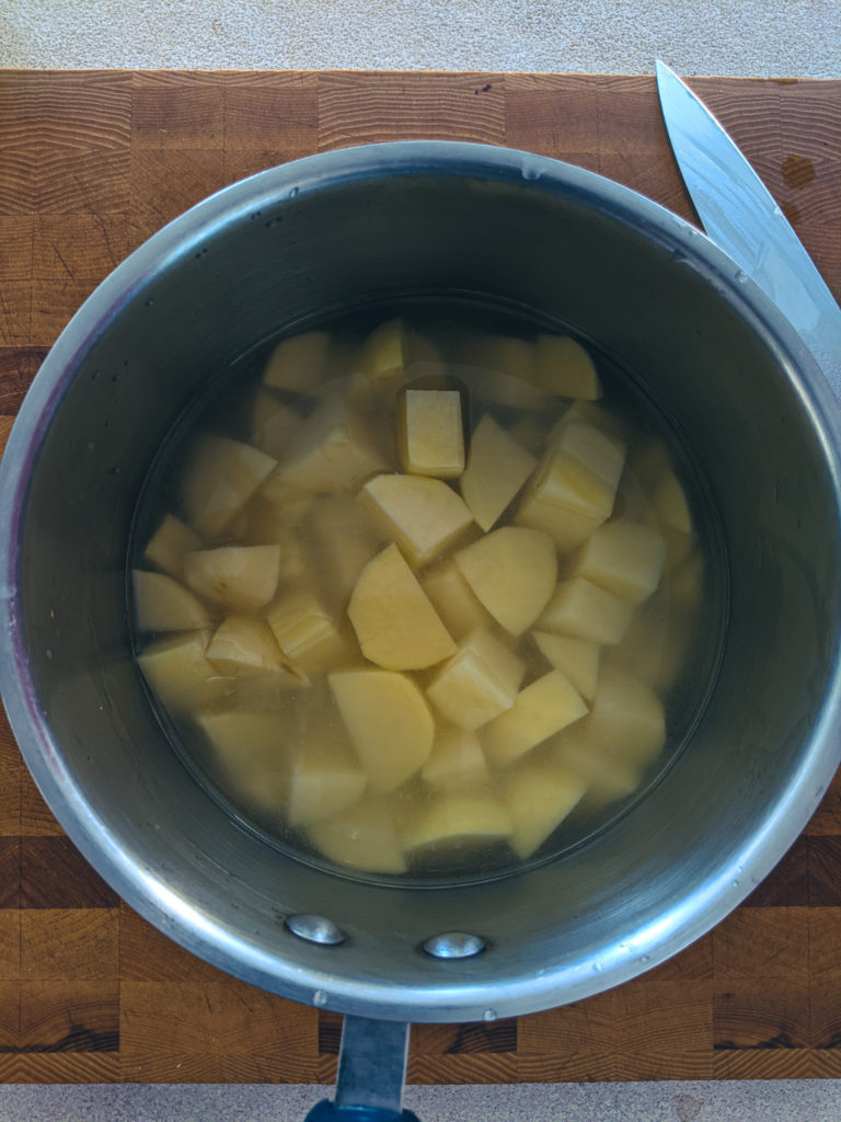Rinsing diced potatoes in a pot of water to remove starch