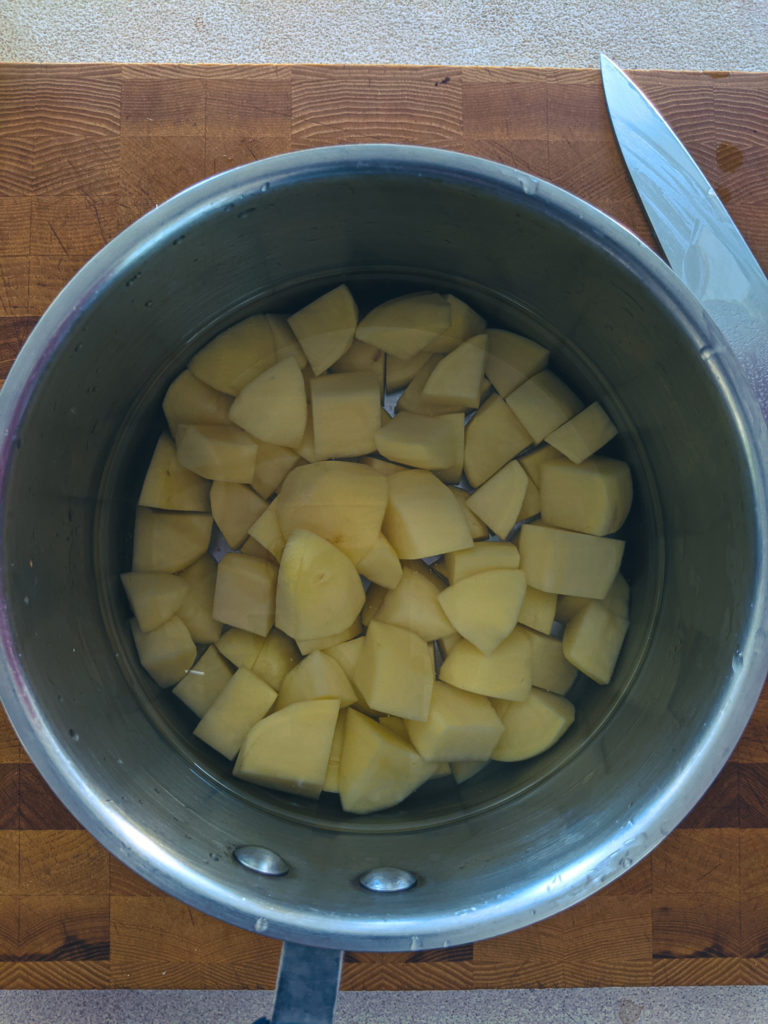 Clear water after third rinse showing potatoes are ready