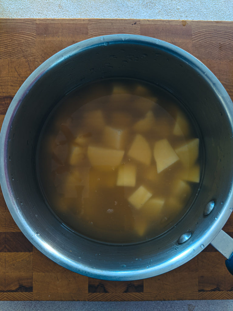 Adding minced garlic to the potatoes and chicken stock