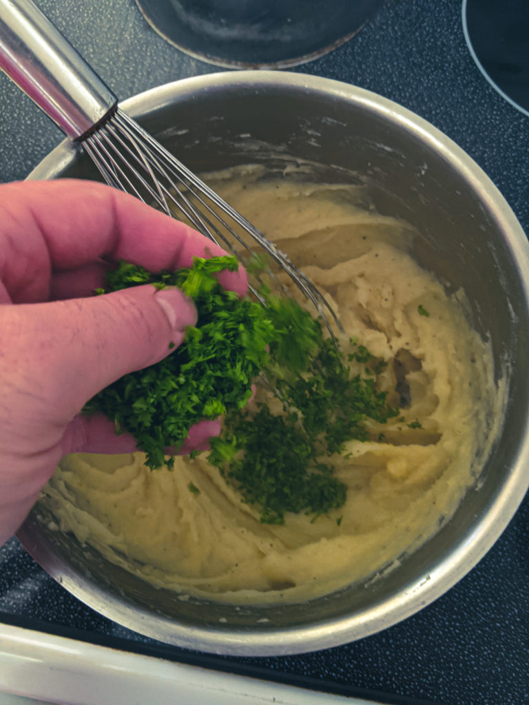 Adding chopped parsley to the finished mashed potatoes