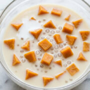 Bowl of Vietnamese sweet potato soup with orange cubes of sweet potato and small tapioca pearls in creamy coconut milk